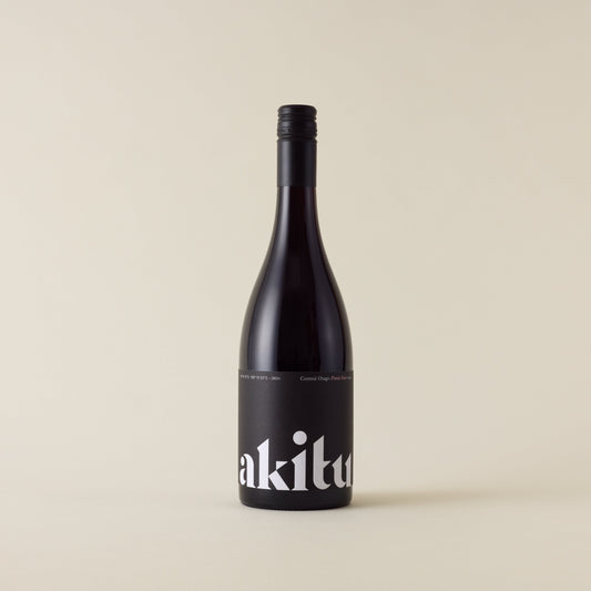 Red wine bottle with pinot noir wine inside. A black label with akitu logo. A black screwtop and neck label.
