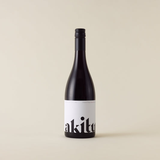 Red wine bottle with pinot noir wine inside. A white label with akitu logo. A black screwtop and neck label. 