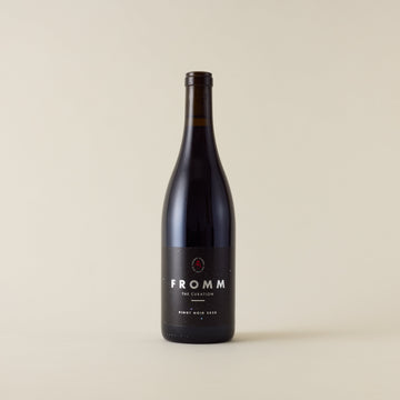 Red wine bottle with pinot noir wine inside. A black label with the Fromm logo.