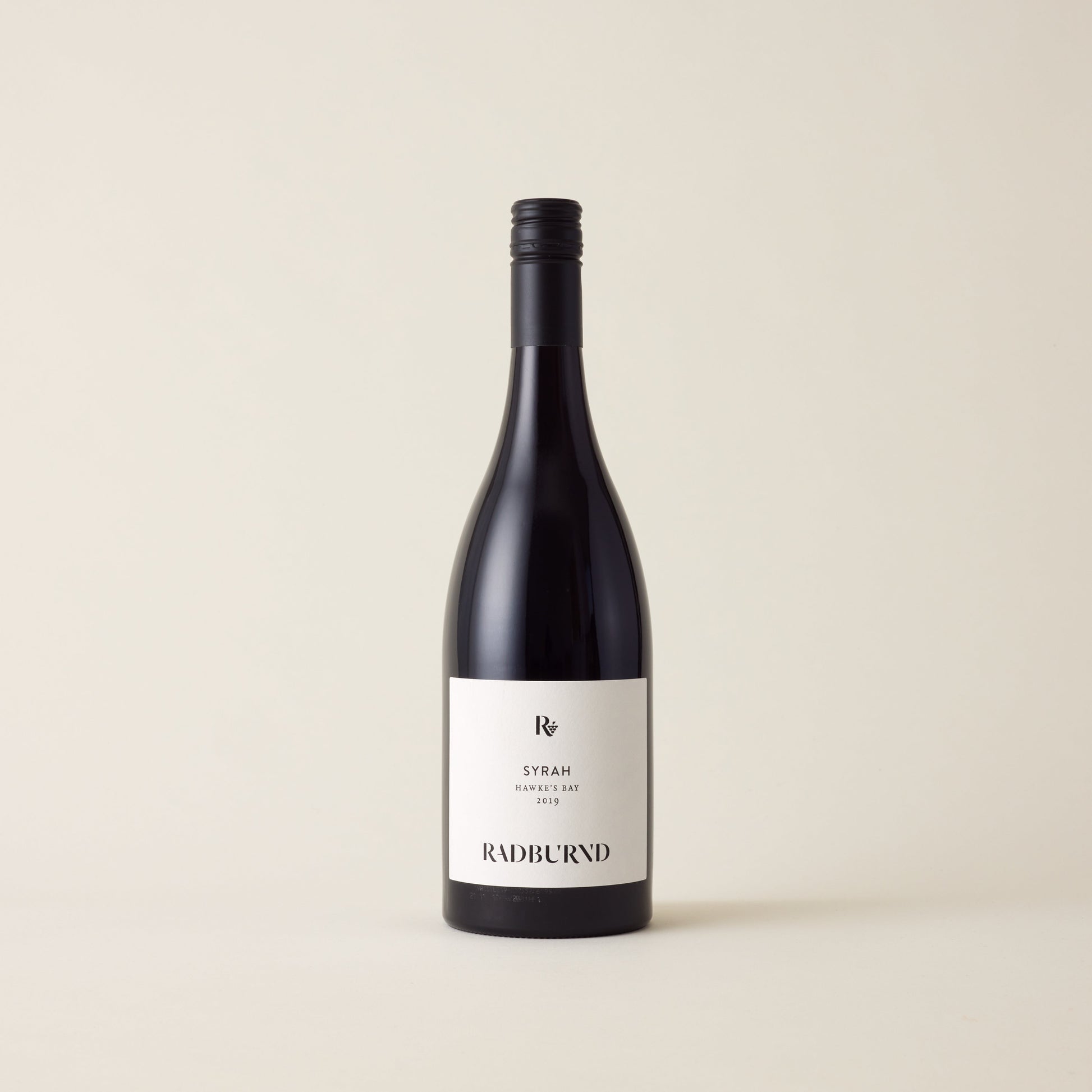 Red wine bottle with Syrah wine inside. A White label with Radburnd logo. A black screwtop and neck label.