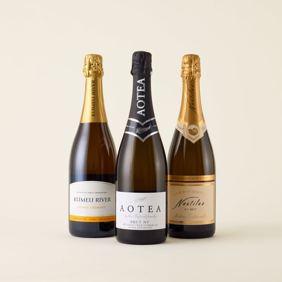 3 sparkling wine bottles with chardonnay and pinor noir grapes in. 
