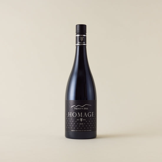 Red wine bottle with syrah wine inside. A black label with Homage logo. A black screwtop and neck label.