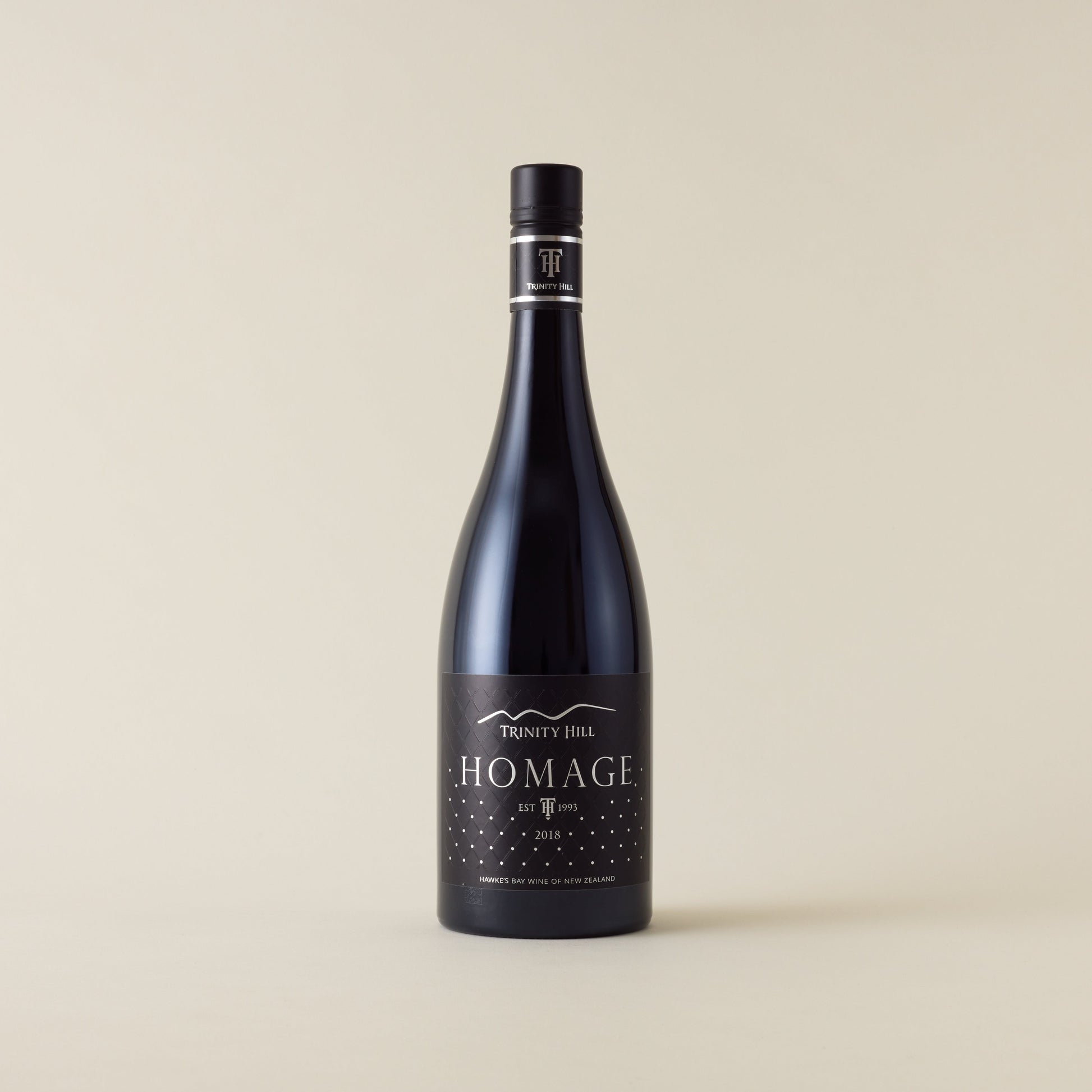 Red wine bottle with syrah wine inside. A black label with Homage logo. A black screwtop and neck label.